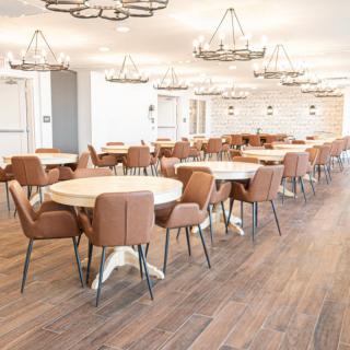 A modern dining area with round tables, upholstered chairs, and elegant chandeliers.