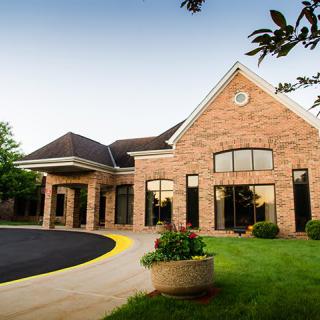 A brick building with large windows and a landscaped entrance.