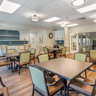 A modern dining room with tables and chairs, featuring contemporary lighting and decor.
