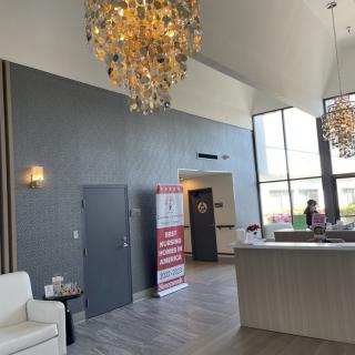 A modern lobby with chandeliers, large windows, and a reception desk.