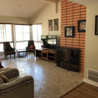 A cozy living room with a television, fireplace, and large windows.