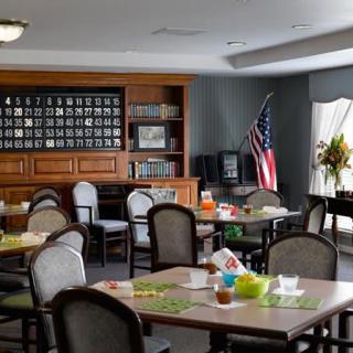 A well-lit dining area with neatly arranged tables and chairs, featuring an American flag and decorative elements.