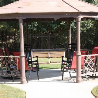 A gazebo with chairs set up in a garden area.