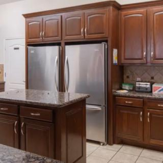 A modern kitchen with wooden cabinets and a stainless steel refrigerator.