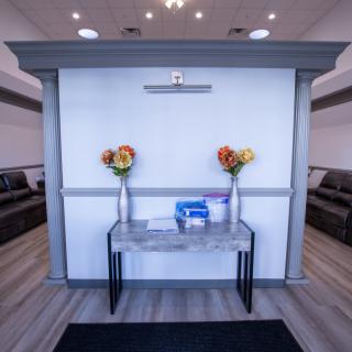 A modern reception area with a table, vases filled with colorful flowers, and comfortable seating.