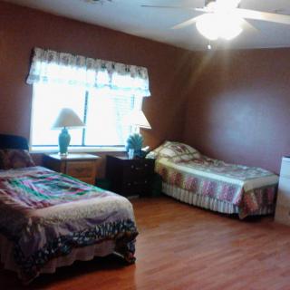 A cozy bedroom featuring two beds, hardwood flooring, and a large window.