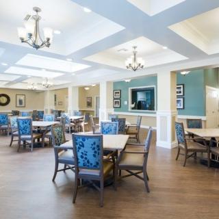 A bright and modern dining room with elegant chandeliers, tables, and chairs arranged neatly.