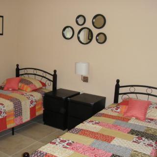 A cozy bedroom with two twin beds adorned with colorful patchwork quilts and decorative wall mirrors.