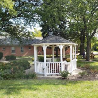 A white gazebo surrounded by lush greenery in a garden setting.