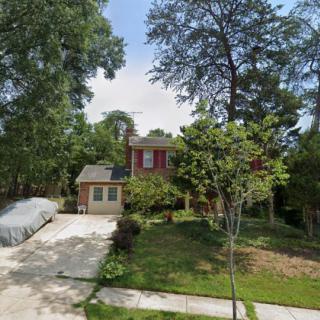 A suburban brick house with a driveway and surrounding trees.