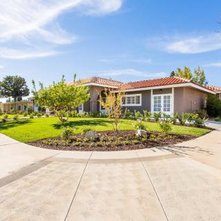 A suburban house with a landscaped garden and a curved driveway under a clear blue sky.