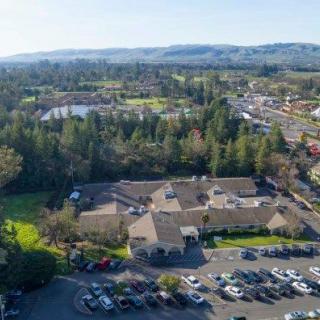 Aerial view of a building complex surrounded by trees and a parking lot, set in a suburban landscape.