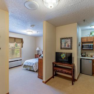 A compact apartment with a cozy bedroom and kitchenette, featuring modern furniture and decor.