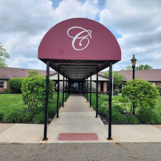 A welcoming entrance with a canopy leading to a beautifully landscaped building.
