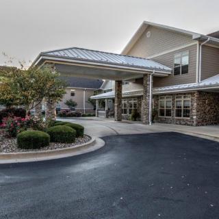 A well-maintained building entrance with a covered driveway and landscaped surroundings.