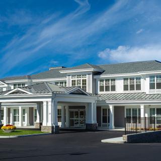 A modern residential building with a spacious entrance under a clear blue sky.