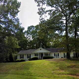 A charming house surrounded by trees and a well-maintained yard.