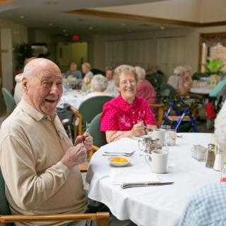 Seniors enjoying a meal together in a communal dining area.