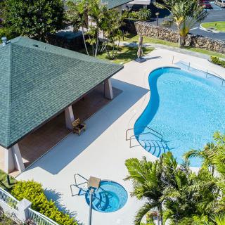 Aerial view of a swimming pool with an adjacent pool house and lush landscaping.