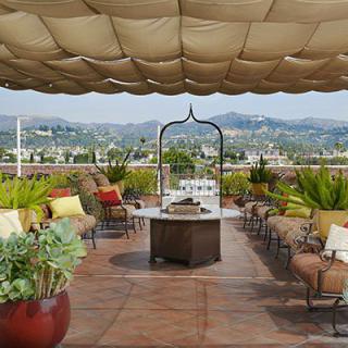 A scenic rooftop patio with comfortable seating, a fire pit, and views of distant mountains.