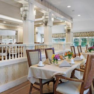 An elegant dining room with a formal table setup, featuring plush chairs and tasteful decor.