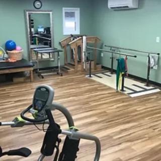 A rehabilitation therapy room equipped with various exercise machines and training tools.