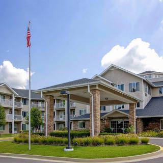 A modern residential apartment building with a well-maintained exterior and surrounding greenery under a blue sky.
