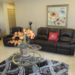A cozy living room with leather seating and floral decor.