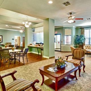 A cozy community lounge with seating and dining areas, adorned with ceiling fans and warm lighting.