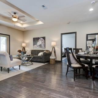 A modern living room and dining area with hardwood flooring, stylish furniture, and elegant lighting.