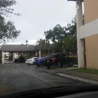 A view of a parking lot with several cars parked near buildings on an overcast day.
