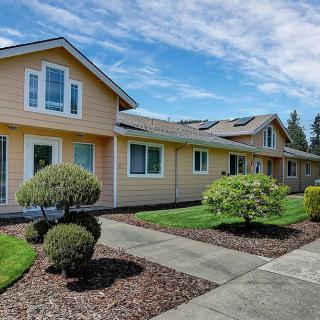 A suburban yellow house with a well-maintained lawn and shrubs.