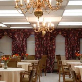 A well-decorated dining room with chandeliers, tables, and floral curtains.