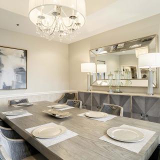 A modern dining room featuring a large wooden table, elegant chandelier, and stylish decor.