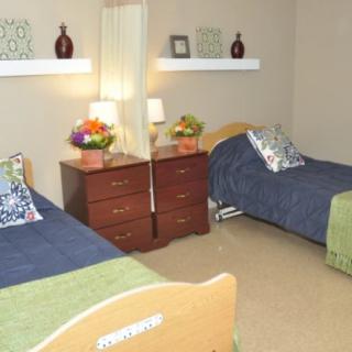 A neatly arranged shared bedroom with two beds, a dresser, and decorative elements.