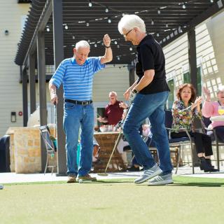 A group of seniors enjoying a dance outdoors during a social gathering.