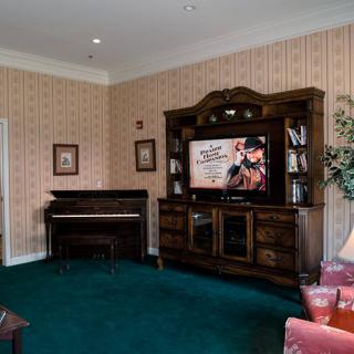 A cozy living room with a piano and an entertainment center featuring a large television.