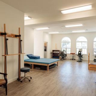 A well-lit physical therapy room equipped with exercise machines and therapy beds.