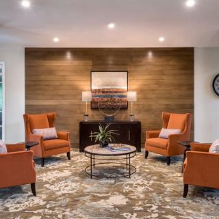 A cozy living room with orange chairs and a wooden accent wall.