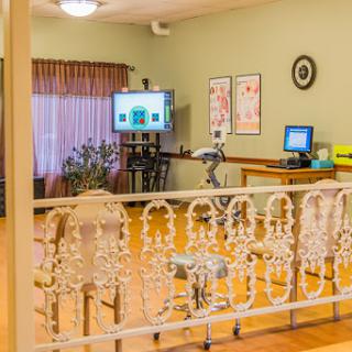 A spacious room equipped with a computer workstation and medical equipment, featuring warm lighting and inviting decor.