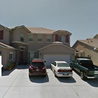 A suburban two-story house with three cars parked in the driveway.