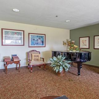 A cozy room featuring a grand piano, elegant furniture, and framed artwork on the walls.