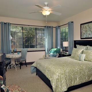 A well-decorated bedroom with a comfortable bed, large windows, and stylish furnishings.