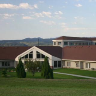 A scenic view of a building with a red roof set against a backdrop of hills and a blue sky.