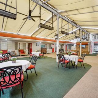 A spacious covered patio with elegantly arranged tables and chairs, perfect for casual dining.