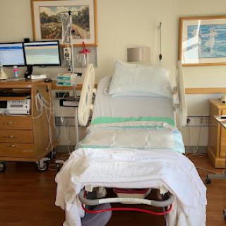 A hospital patient room set up for monitoring, featuring a bed and medical equipment.