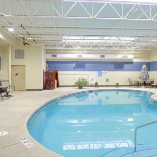 An indoor swimming pool with seating area and tiled flooring.