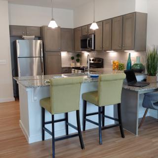 Modern kitchen with stainless steel appliances and a central island featuring bar stools.