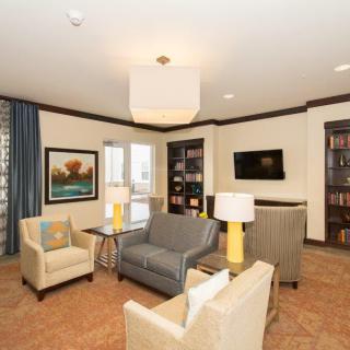 A cozy living room with sofas, chairs, bookshelves, and a mounted television.