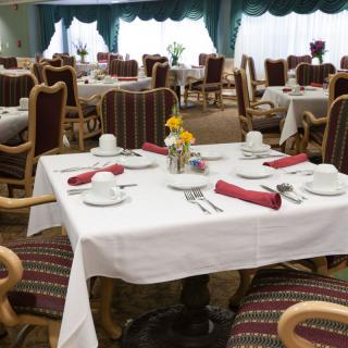 A well-arranged dining room with elegantly set tables and chairs, ready for guests.
